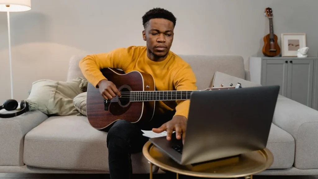 Photo of man writing a song on his laptop