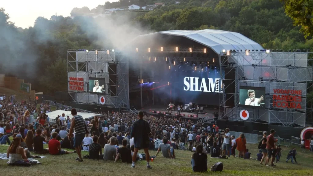 Image of stage on open grass patch with audience